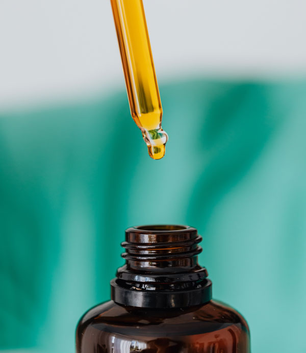Botella de aceite de CBD con gotero y hojas de cannabis